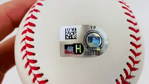 Tilting a baseball to reveal the letters of the MLB hologram validation code, changing from H to X